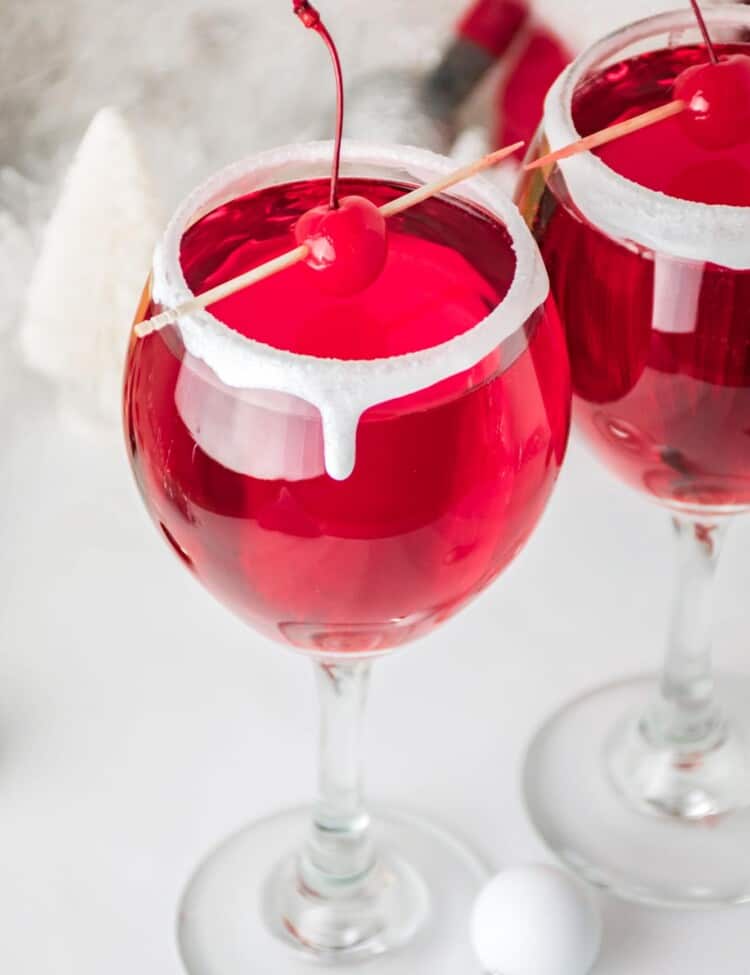 Christmas themed cocktails with maraschino cherries on a pick