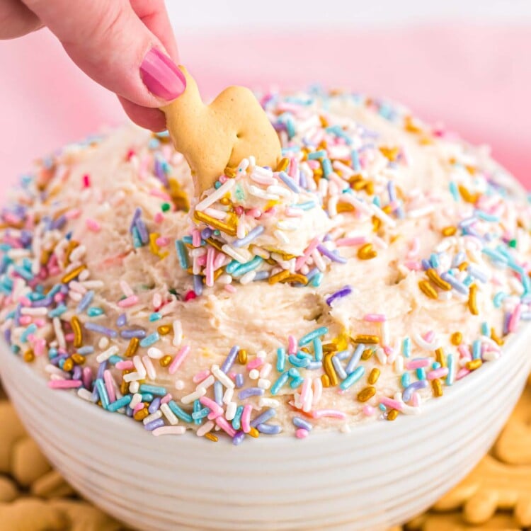 Dipping animal cracker into funfetti cake batter dip, decorated with sprinkles and served with animal crackers.