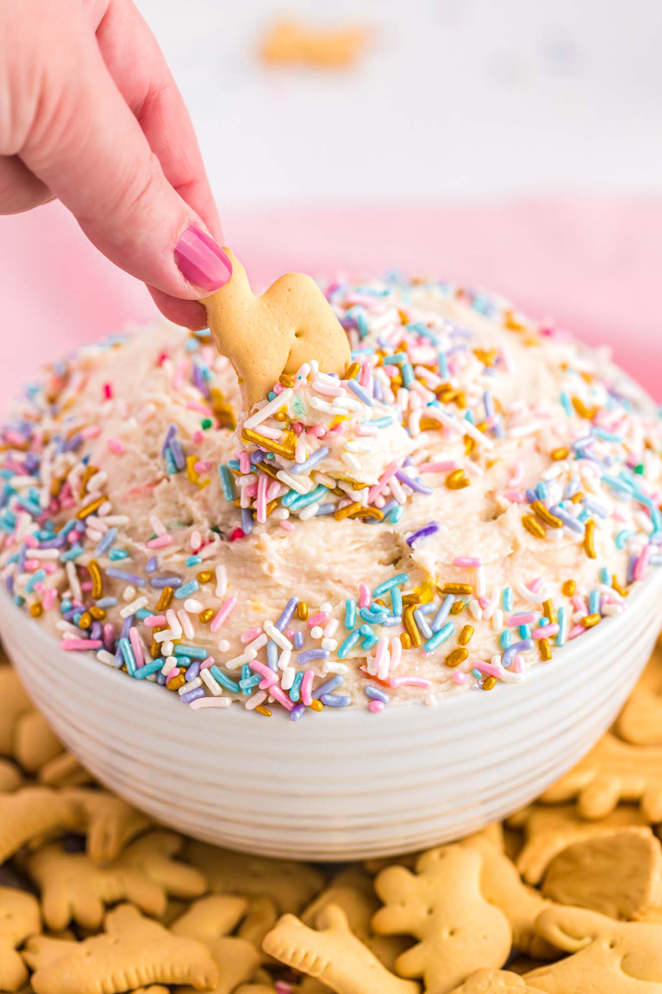 Dipping animal cracker into funfetti cake batter dip, decorated with sprinkles and served with animal crackers.