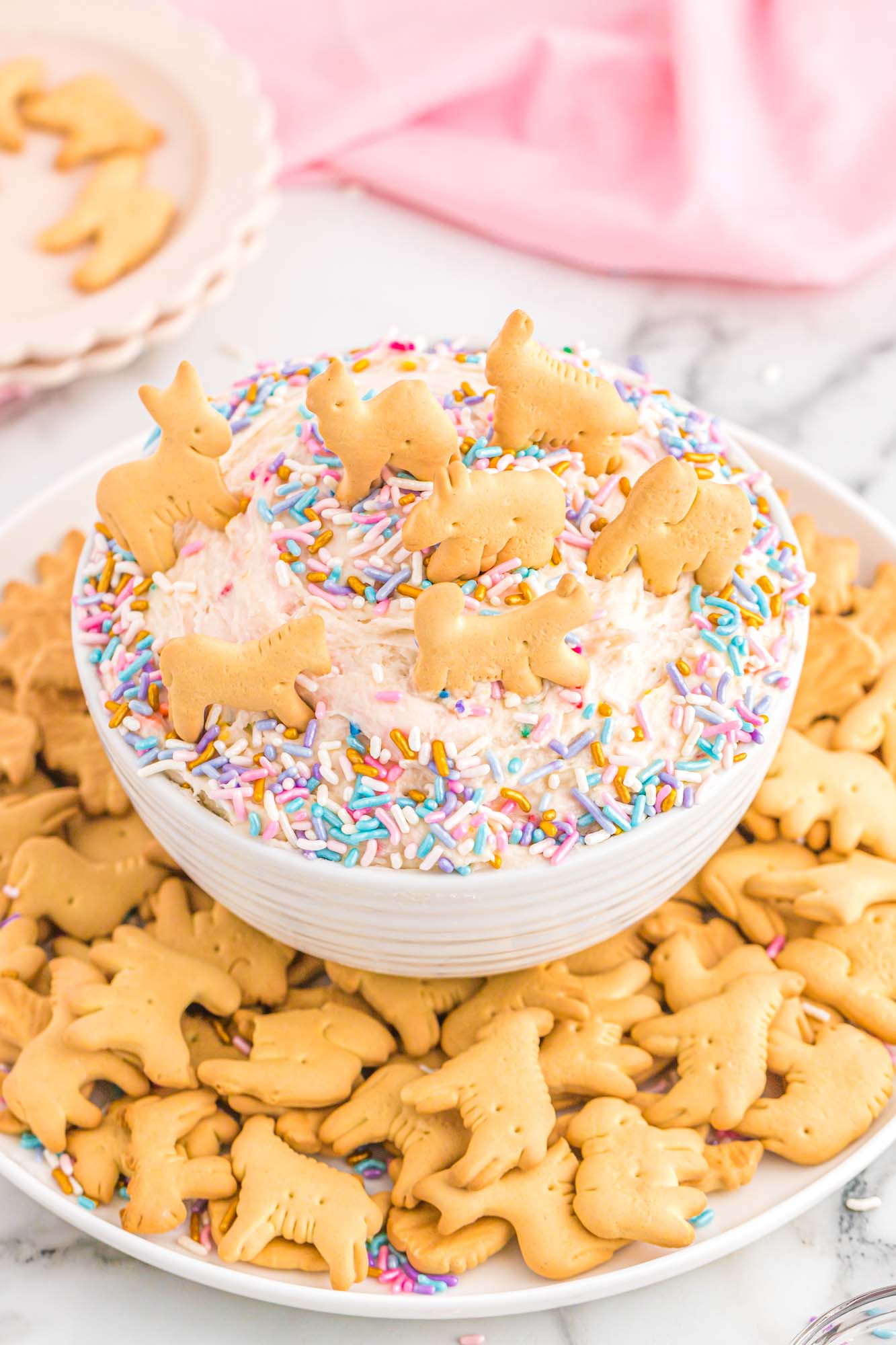 Bowl with funfetti dip and sprinkles, served with animal crackers on the side.