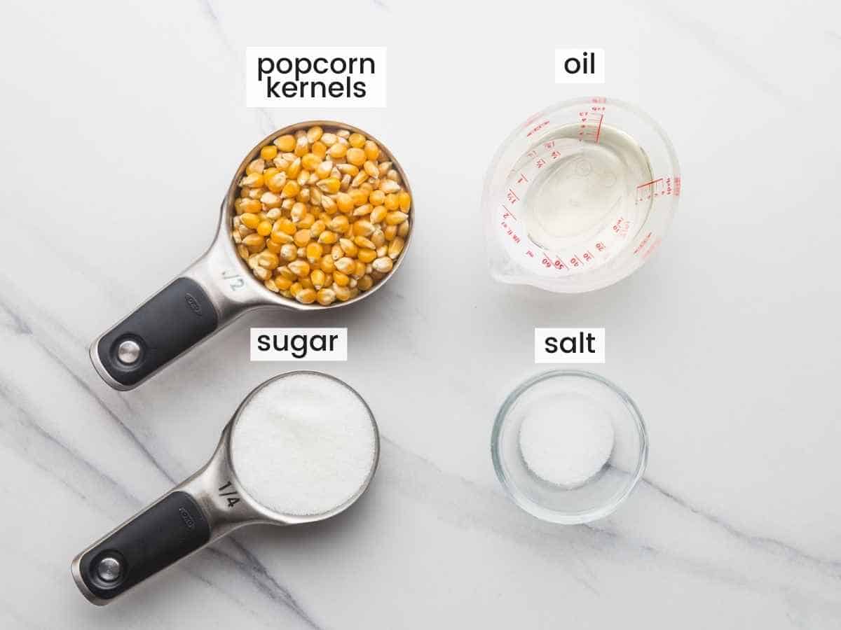 Ingredients needed for making kettle corn: popcorn kernels, sugar, salt, and oil.