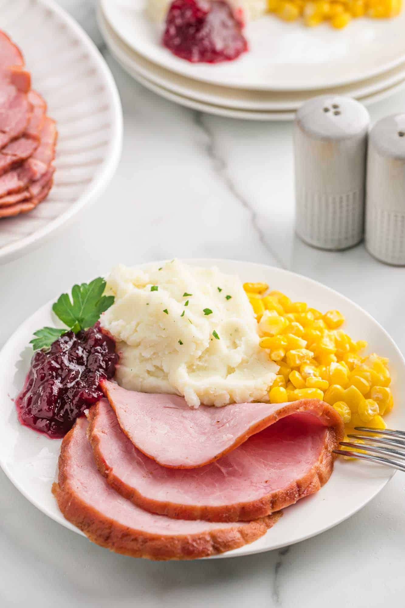 Plated pineapple ham, with mashed potatoes, corn, and cranberry sauce.