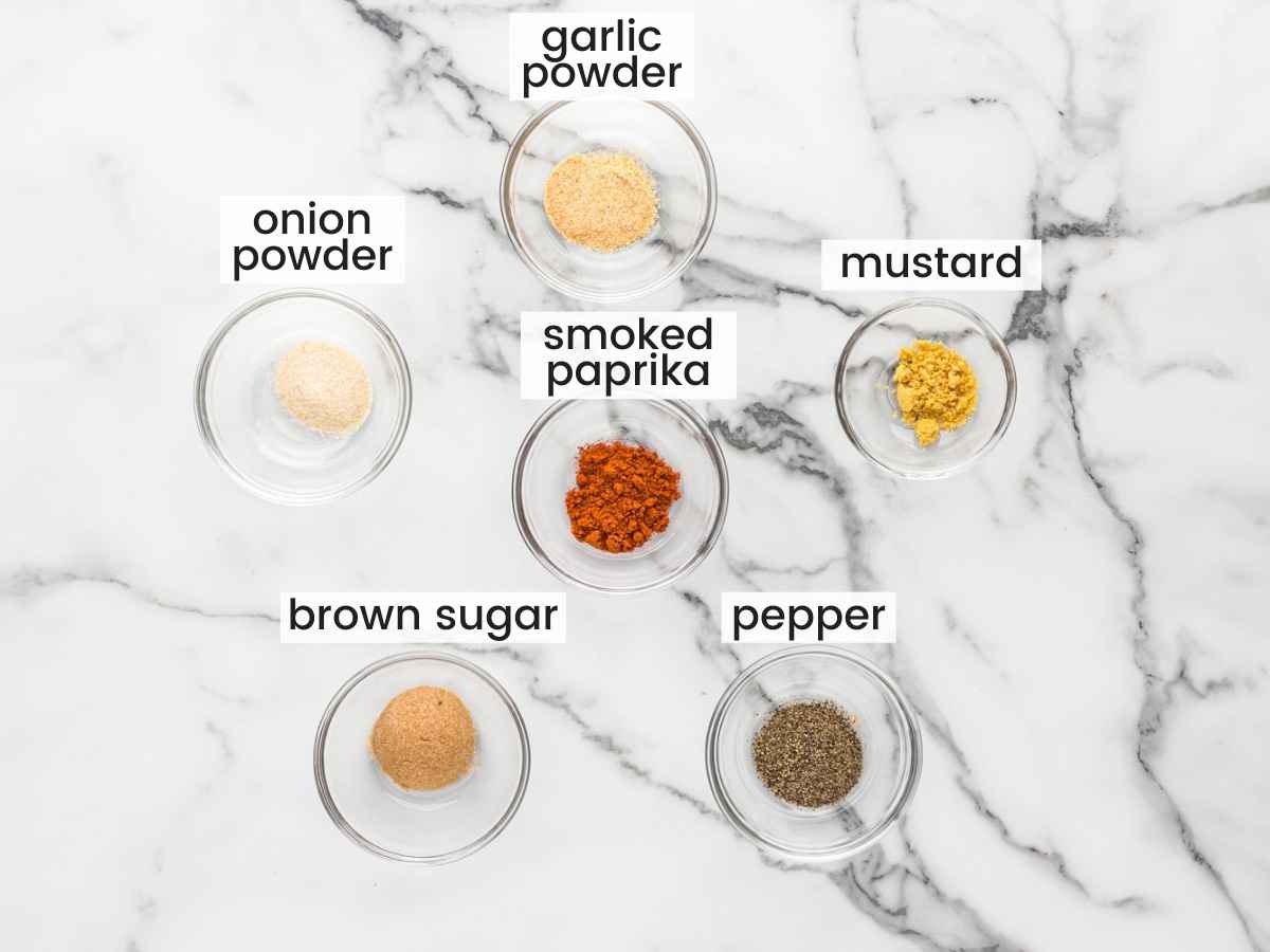 Ingredients needed to make dry rub for pork chops including brown sugar, garlic and onion powders, mustard powder, smoked paprika, and pepper.