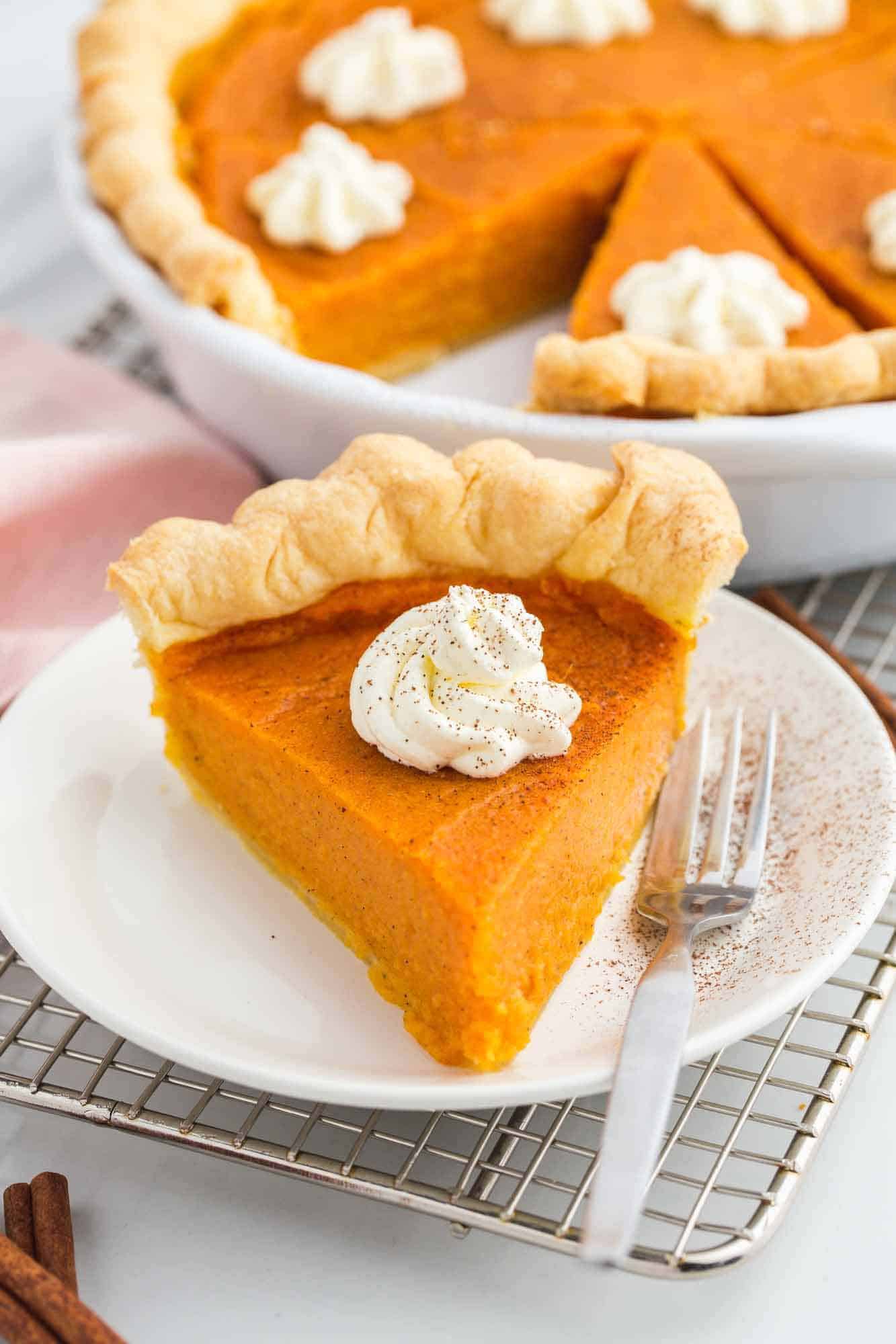 Sweet Potato Slice on a white plate with a fork, and the whole pie in the pie dish in the background