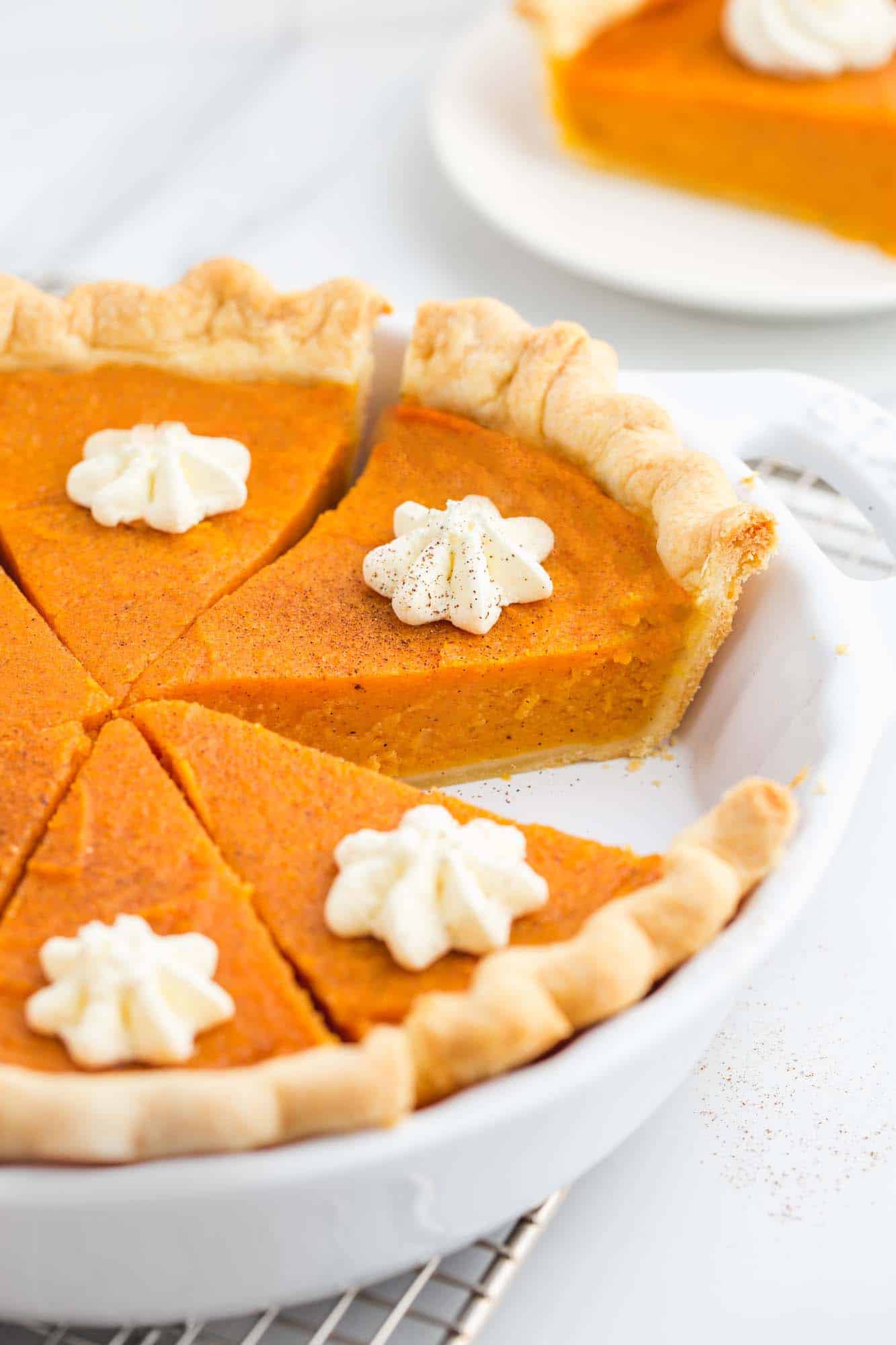 Sliced sweet potato pie in a pie dish, topped with whipped cream stars