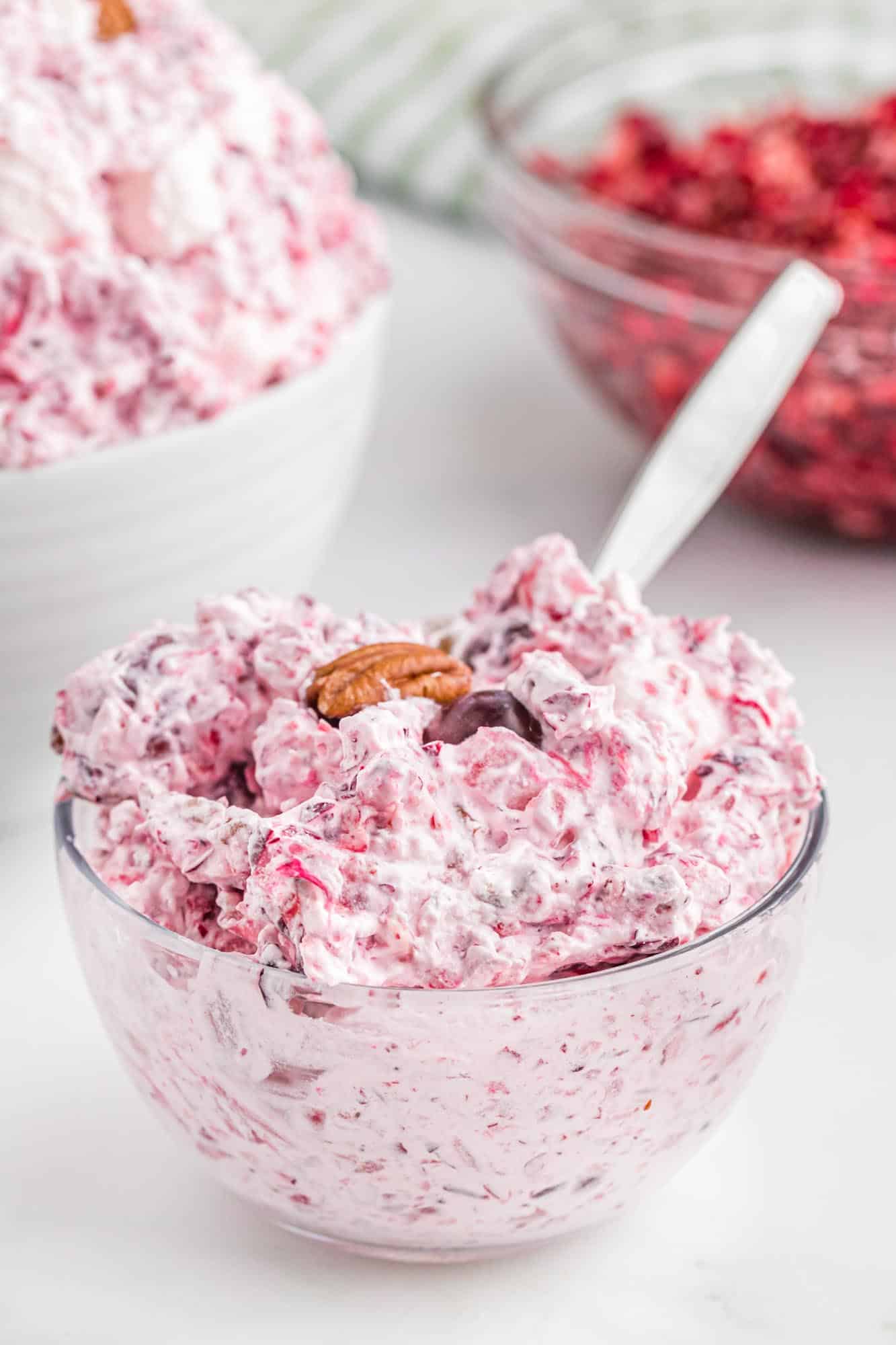 Cranberry fluff salad in a small glass bowl with a spoon