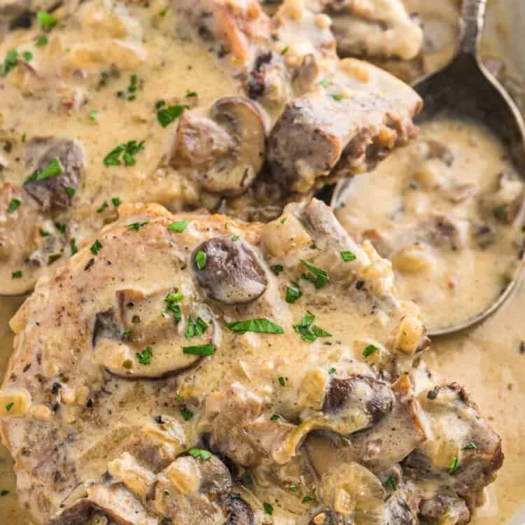 Perfectly cooked bone in pork chops in mushroom gravy served in a white dish
