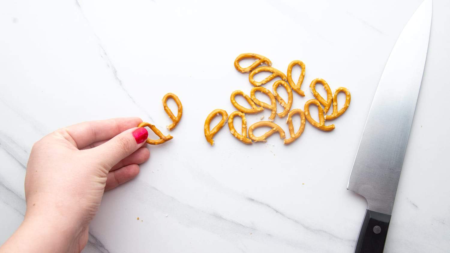 Cutting pretzels with a knife to create reindeer antlers