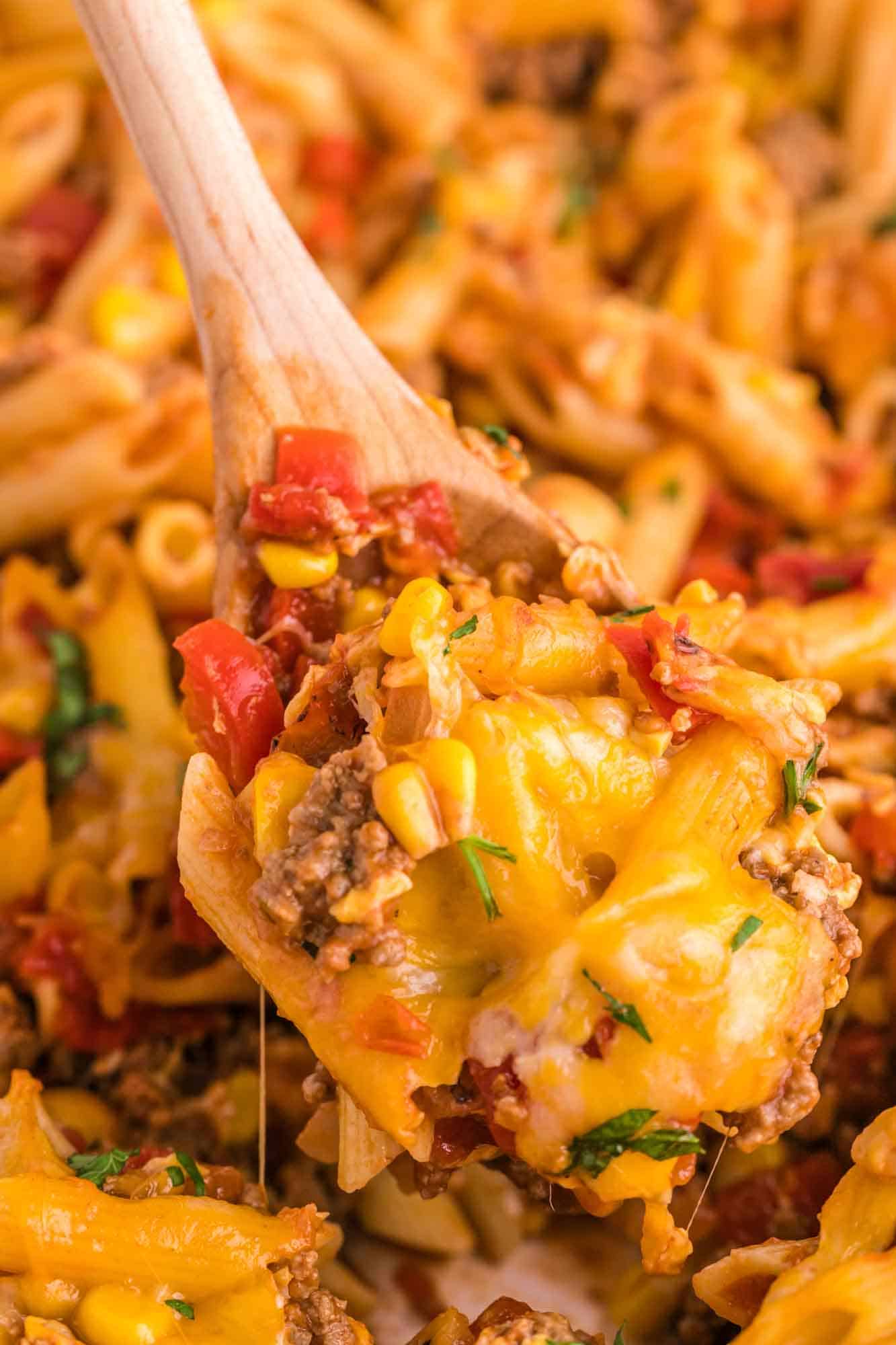 Close up shot of cheesy sloppy joe casserole served with a wooden spoon