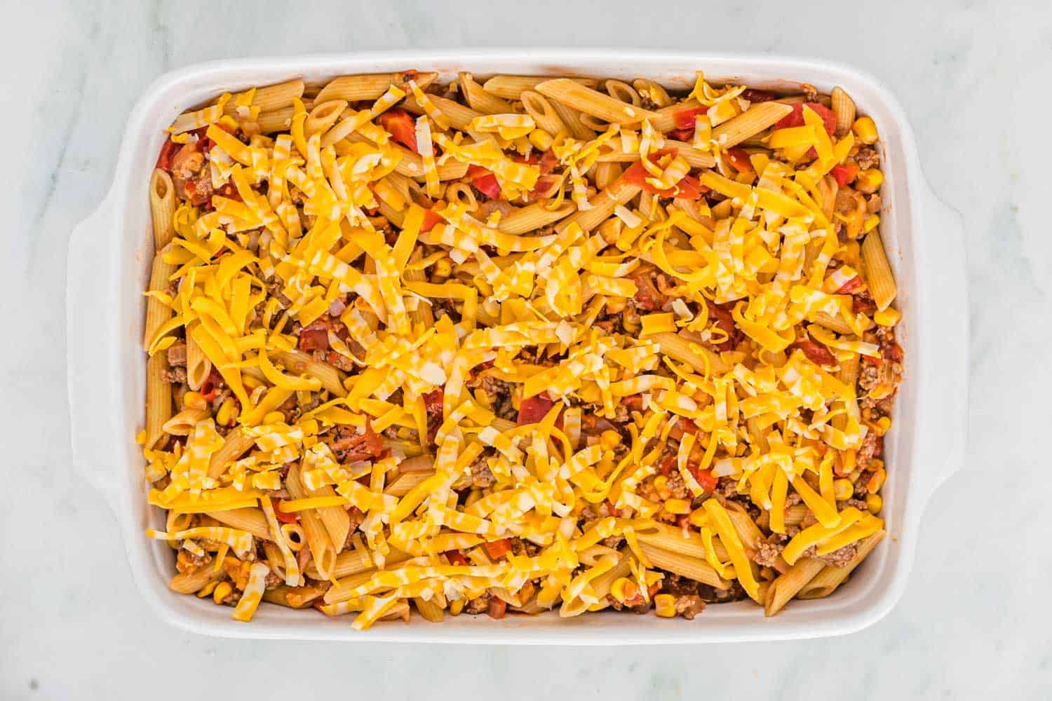 Sloppy Joe Casserole topped with cheese before baking.