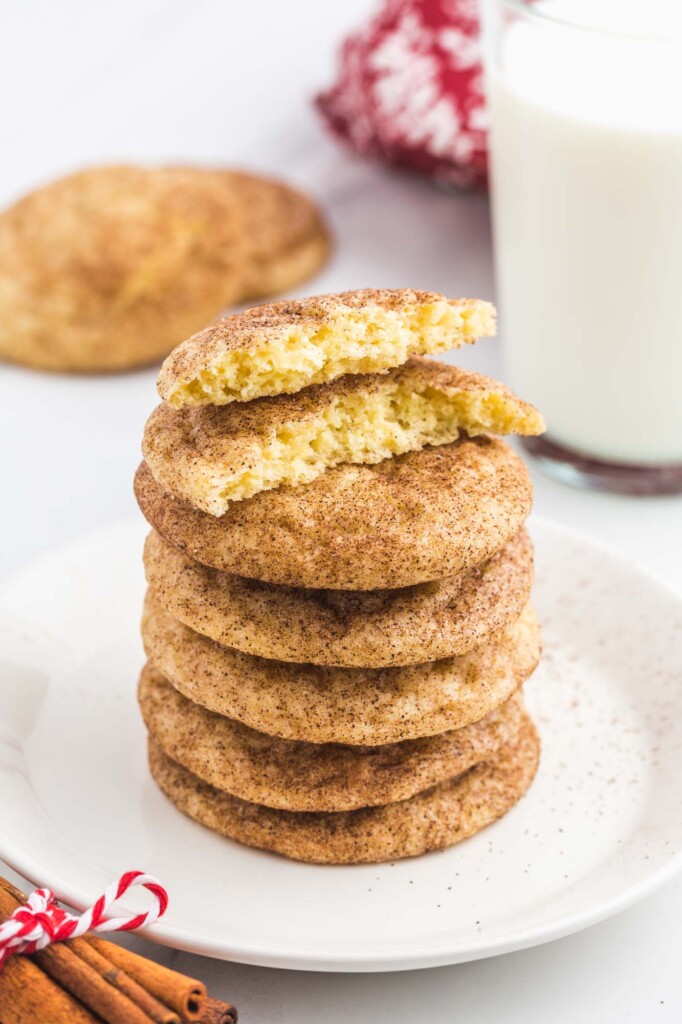 Stack of snickerdoodle cookies, with one bite shot and a glass of milk in the background.