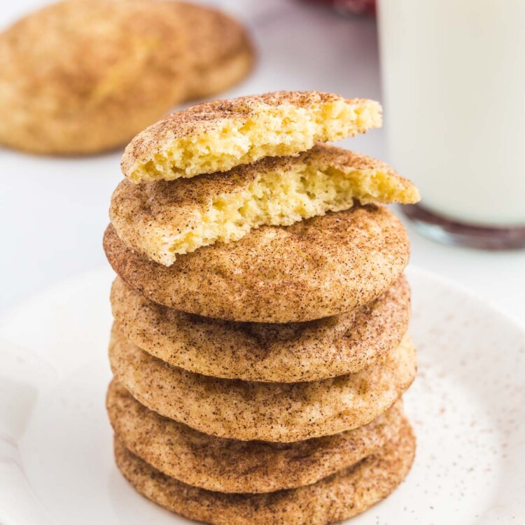Stack of snickerdoodle cookies, with one bite shot and a glass of milk in the background.
