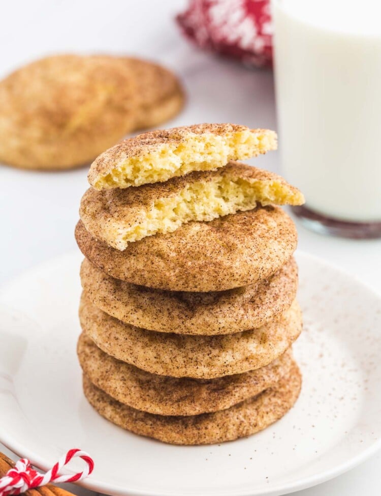 Stack of snickerdoodle cookies, with one bite shot and a glass of milk in the background.