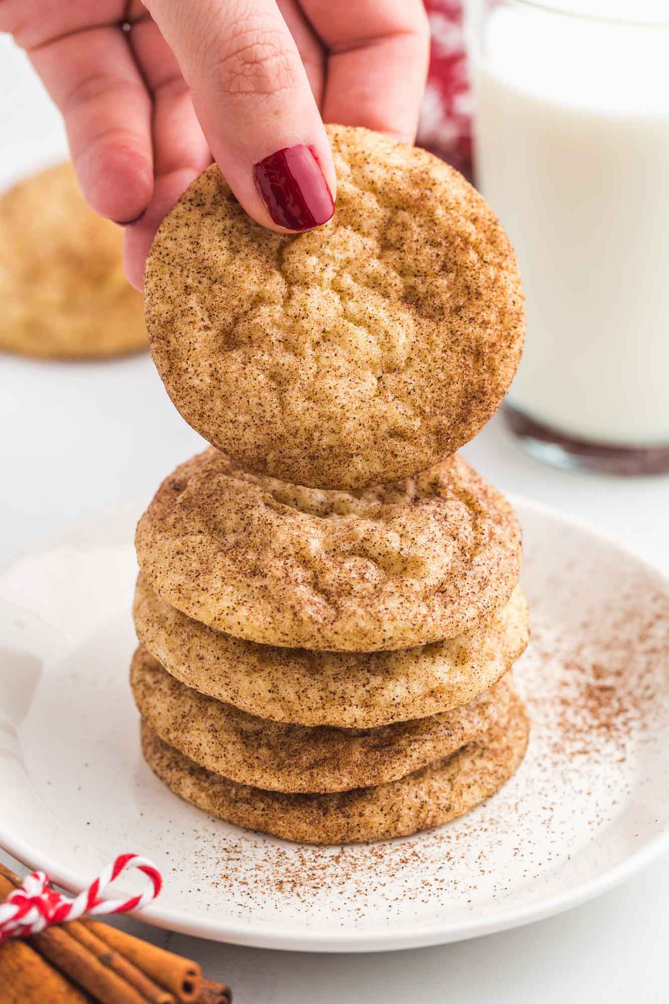 Taking a snickerdoodle from a stack of cookies on a white plate