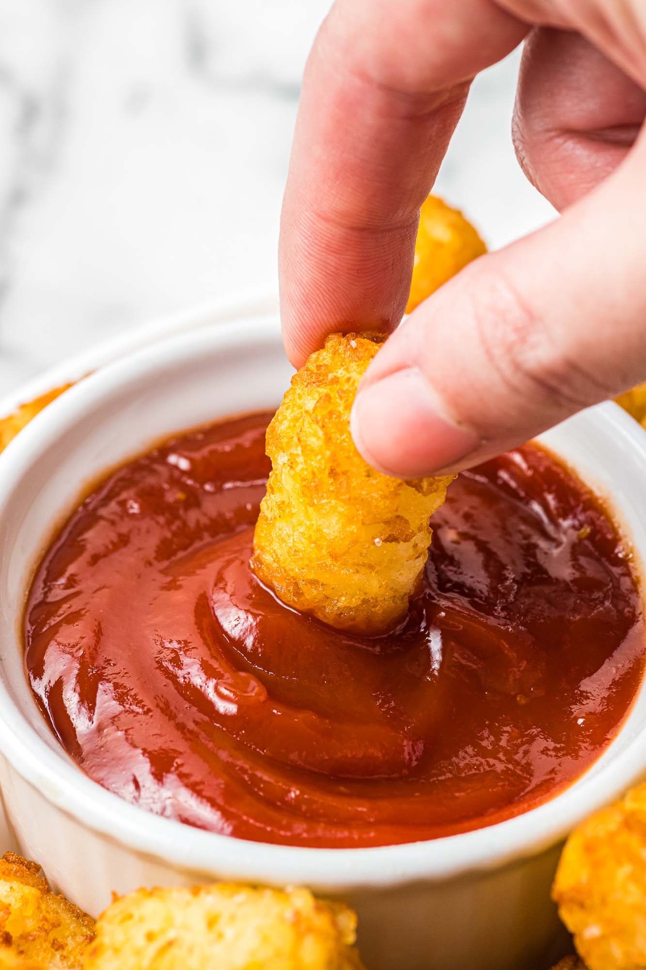 Dipping a tater tot in ketchup