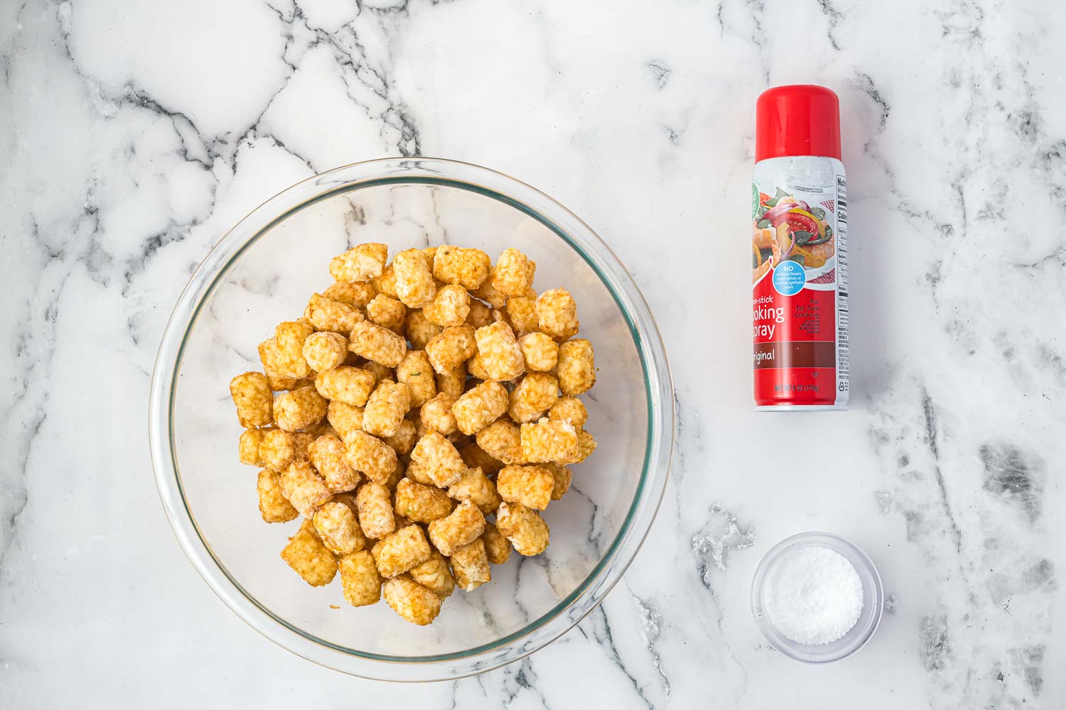 Ingredients needed to air fry tater tots including frozen tater tots, cooking spray, and salt.