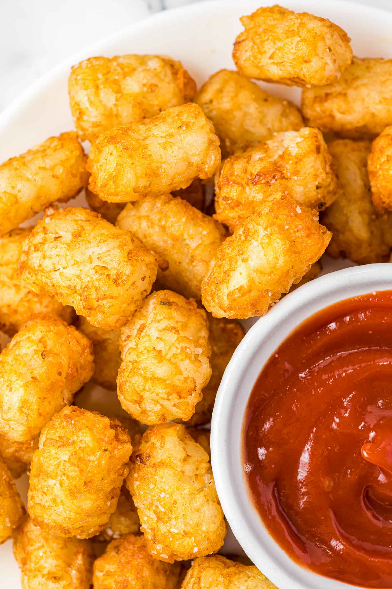 Overhead shot of crispy golden tater tots served with a small bowl of ketchup.