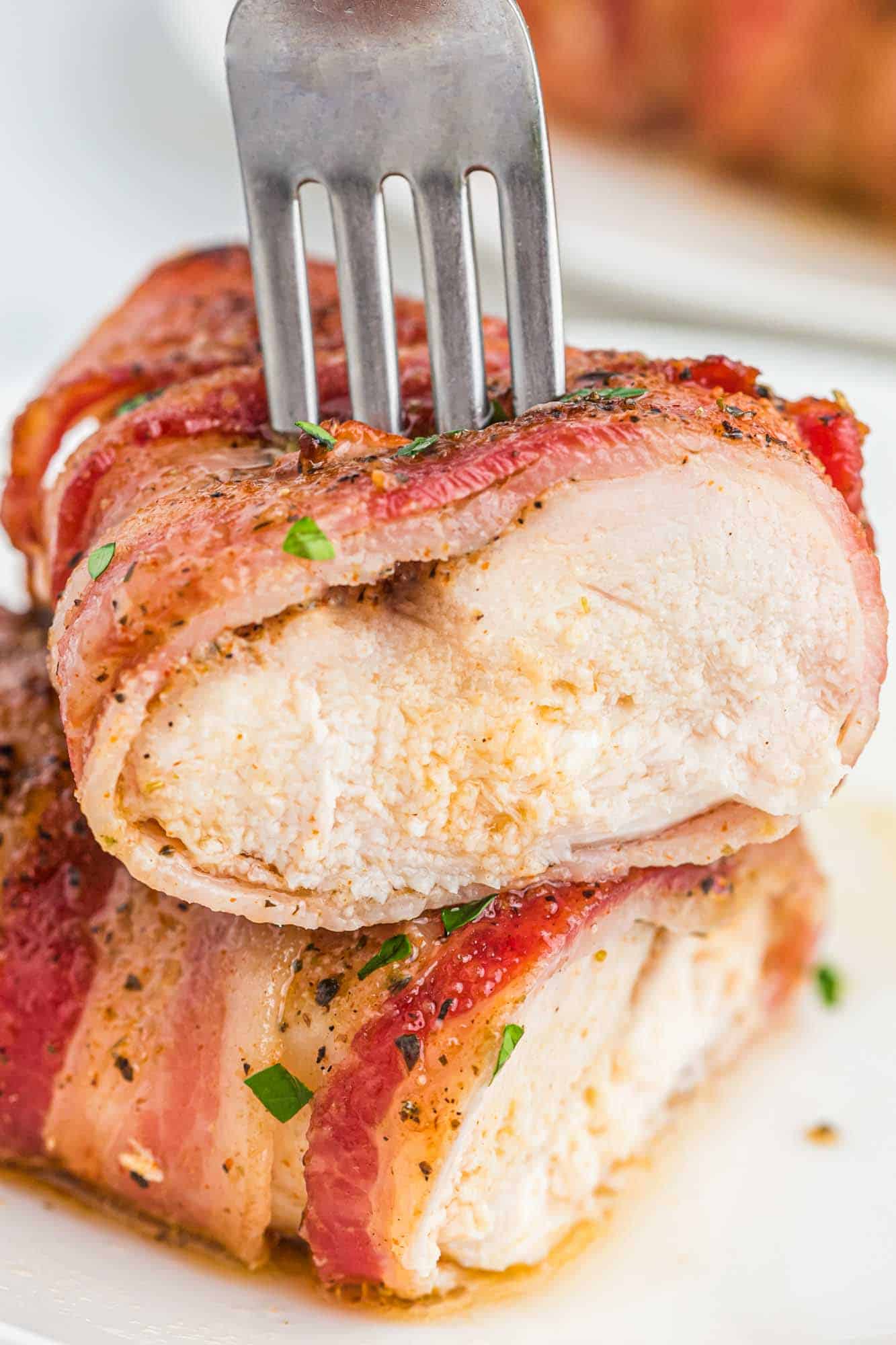 Showing sliced bacon wrapped chicken with a fork