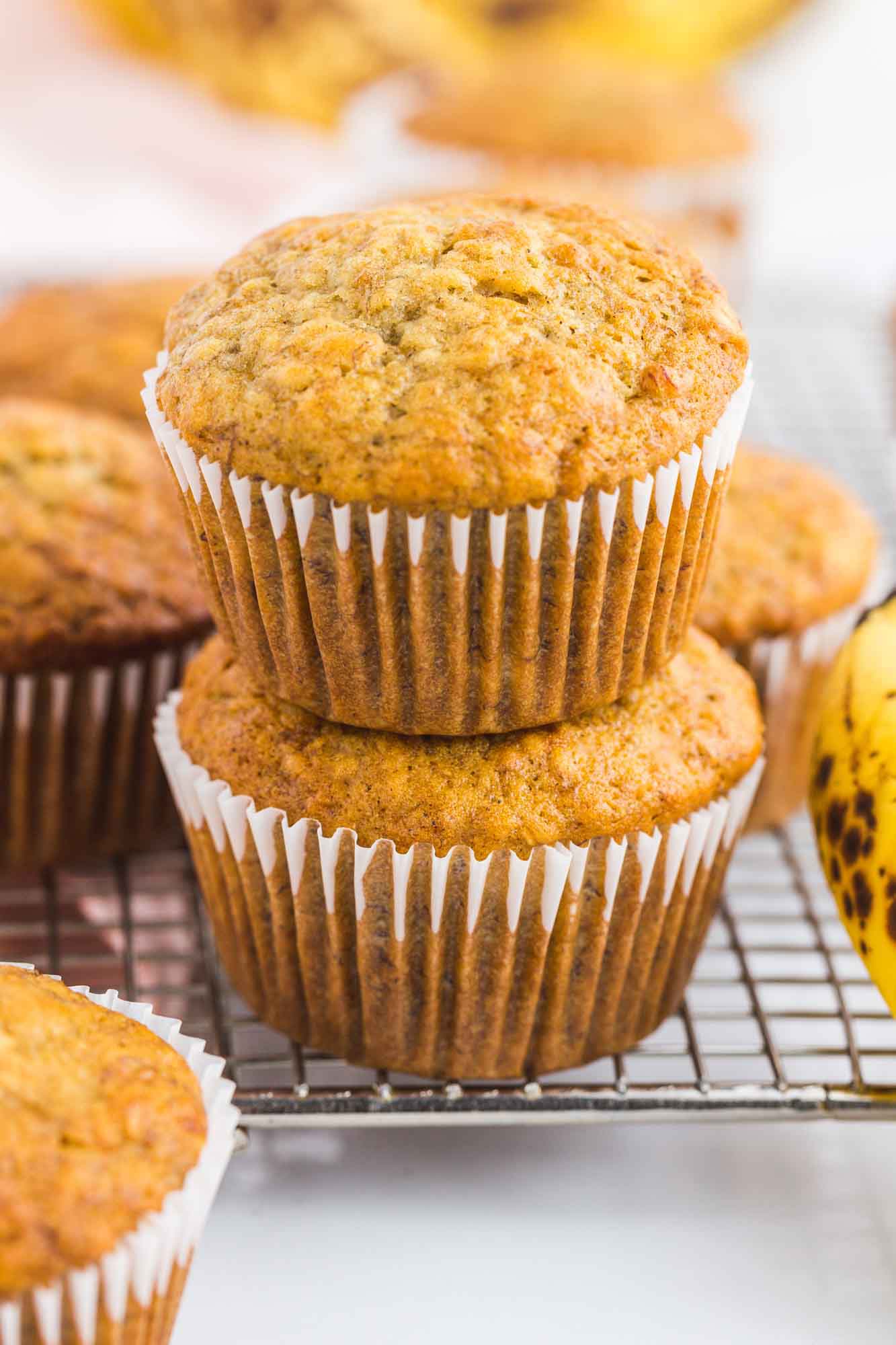 Two stacked banana muffins placed on a cooling rack