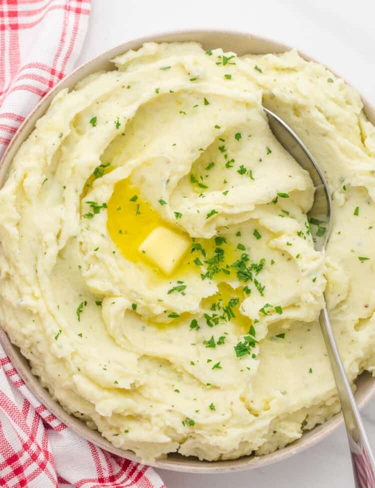 Overhead shot of creamy mashed potatoes in a shallow dish, with a spoon on the side.