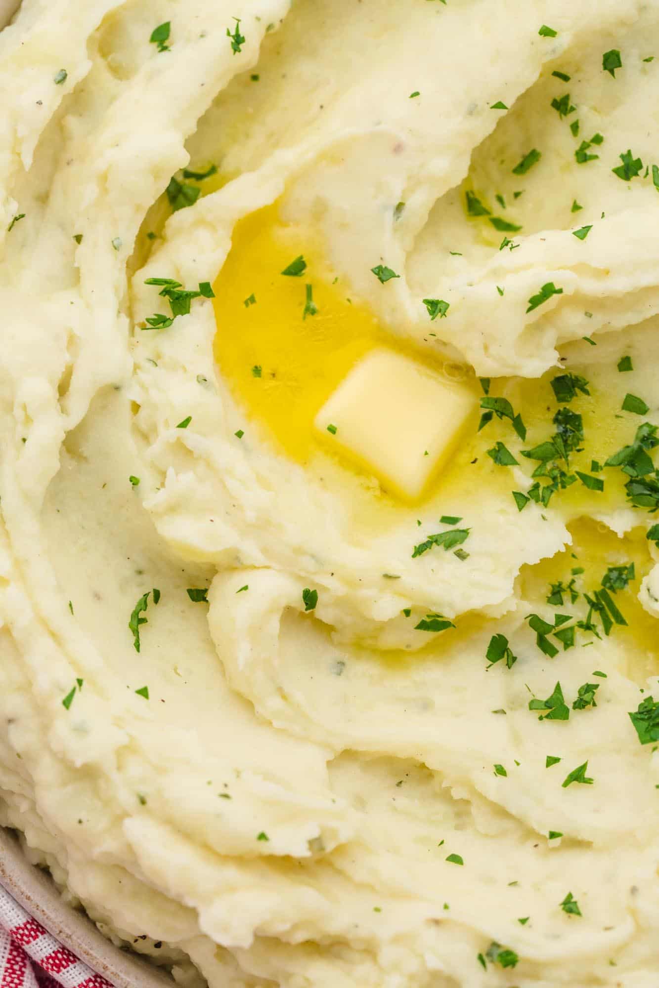 Close up shot of the boursin mashed potatoes, with butter, and chopped parsley.
