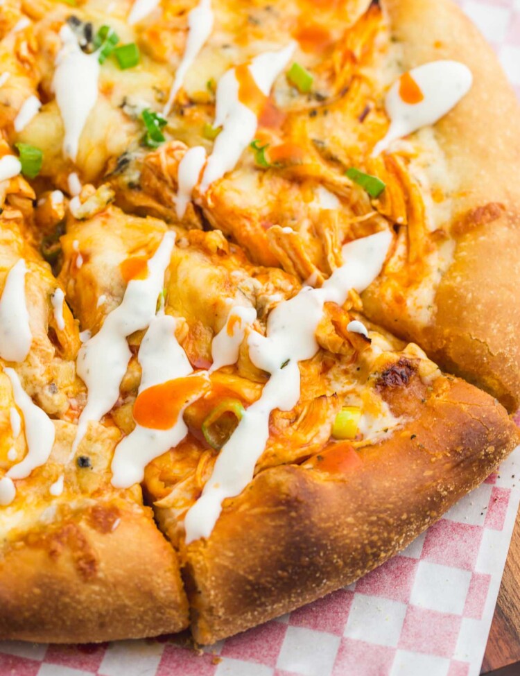 A slice of buffalo chicken pizza drizzled with ranch dressing