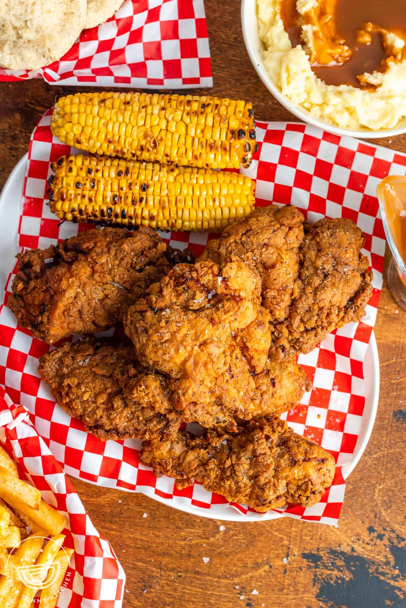 Overhead shot of fried chicken on a platter, with 2 pieces of corn on the cob