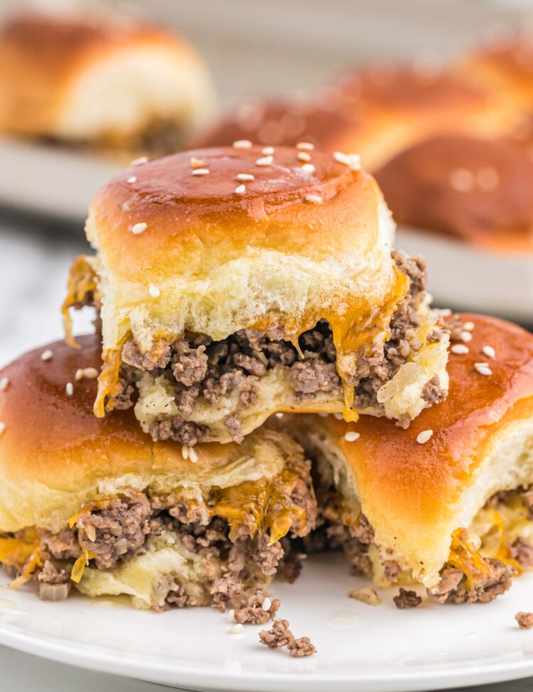 Three cheeseburger sliders stacked on a white plate