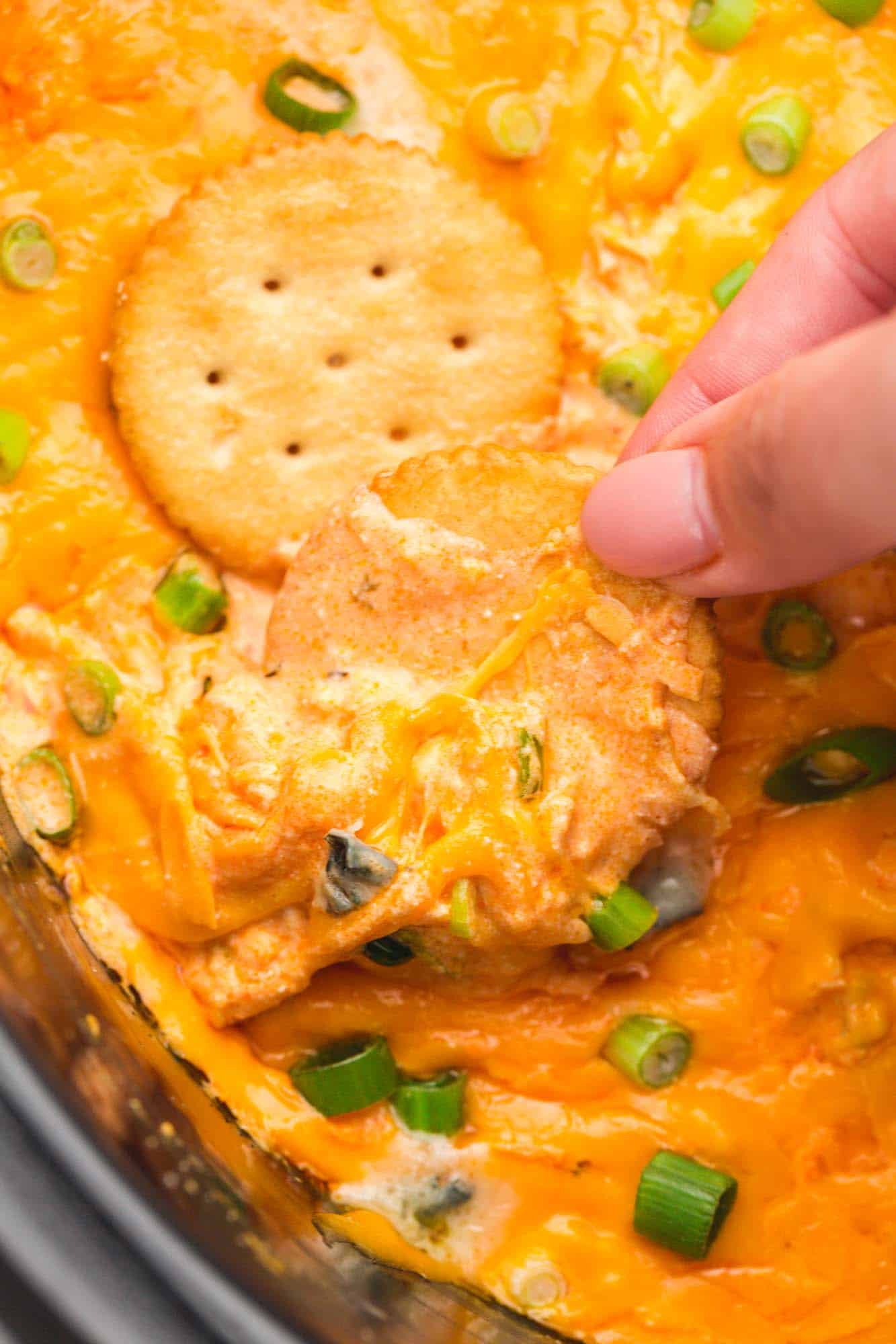 Dipping Ritz crackers in buffalo chicken dip in the slow cooker