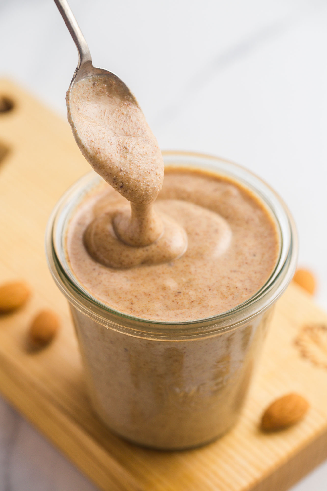 Runny (fresh) almond butter in a glass Weck jar and a spoon