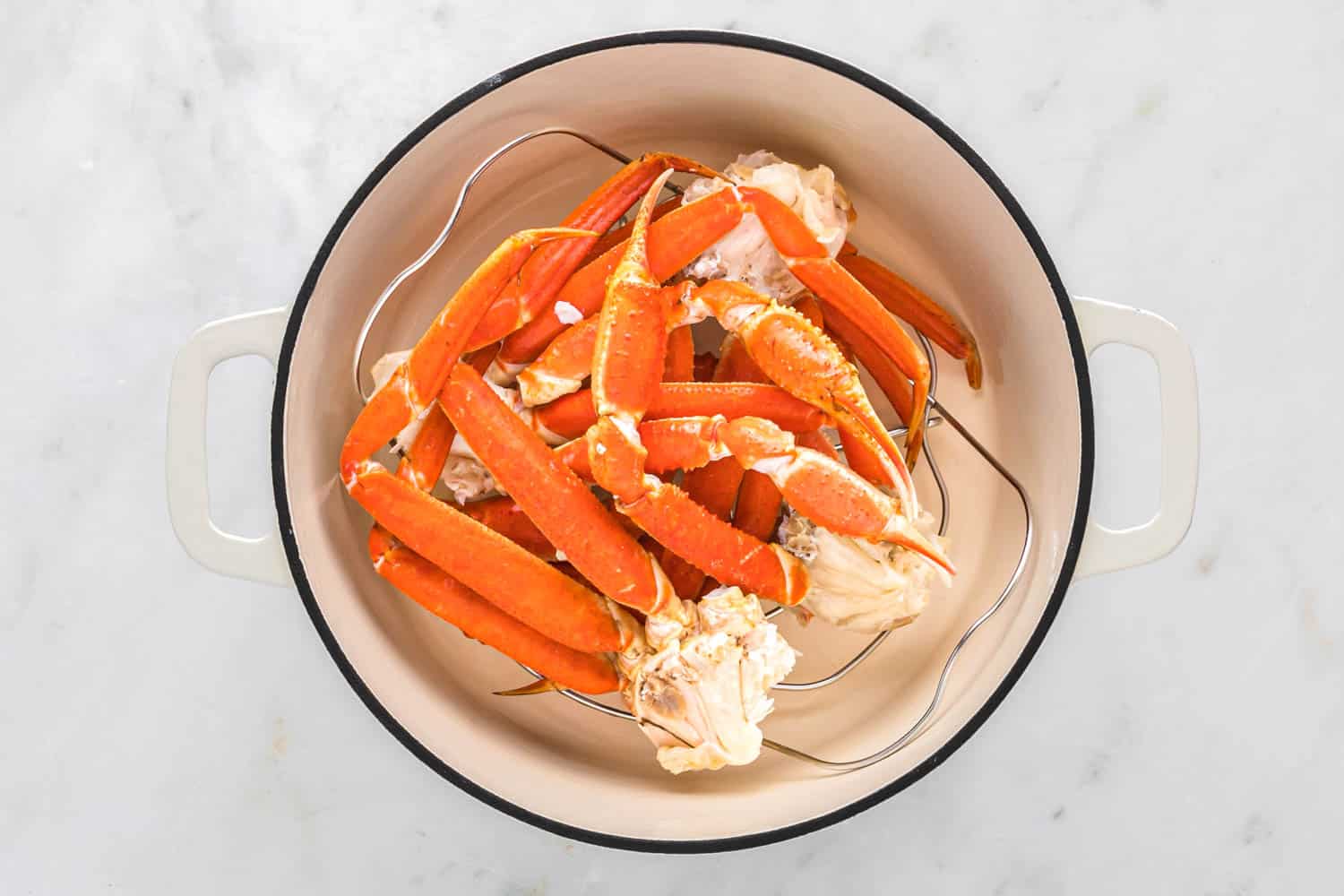 Crab legs placed on a trivet in a dutch oven for steaming