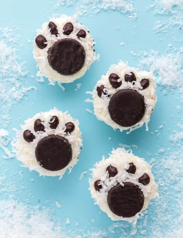 Overhead shot of polar bear paw cupcakes placed on a blue background