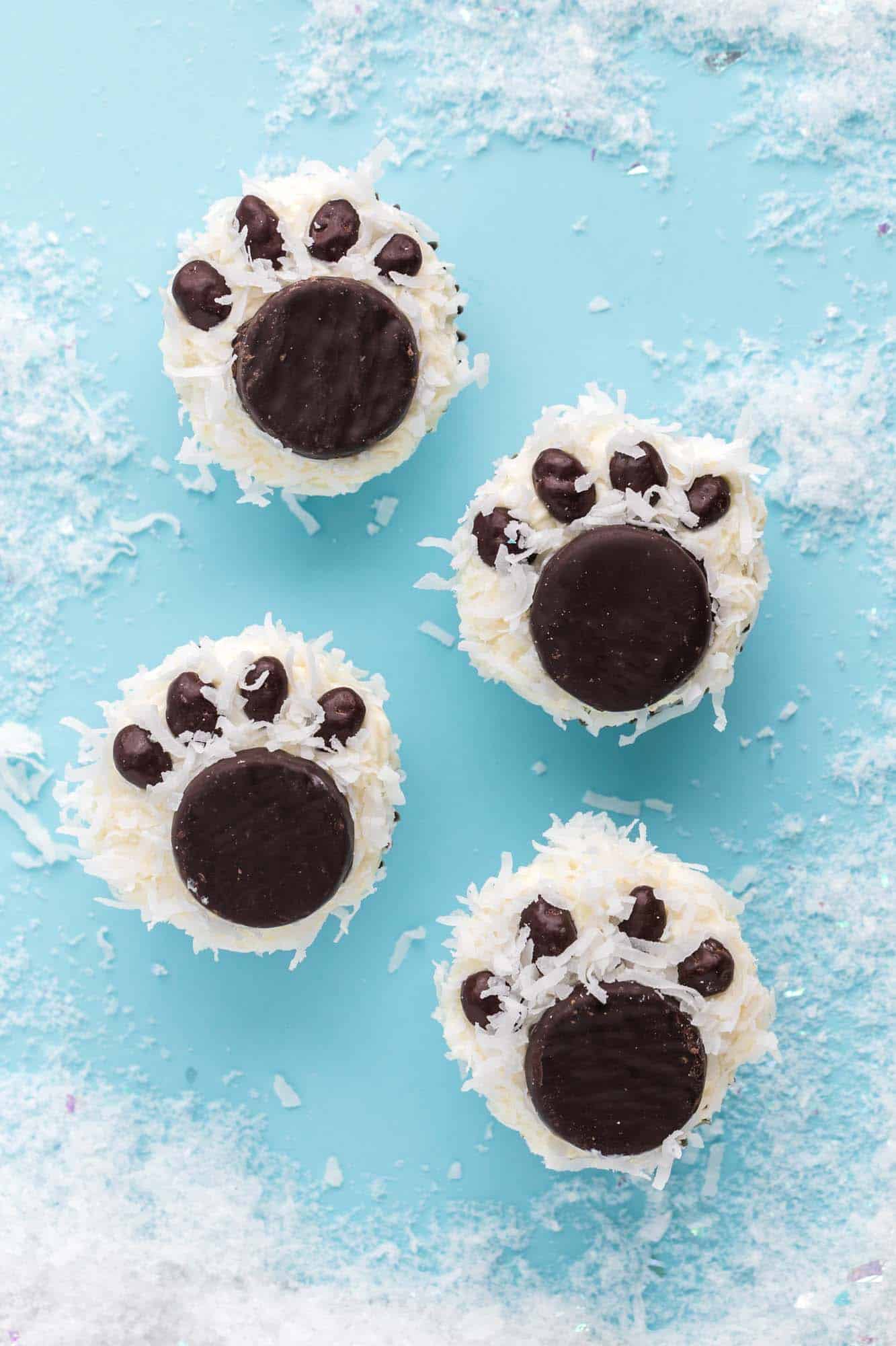 Overhead shot of polar bear paw cupcakes placed on a blue background