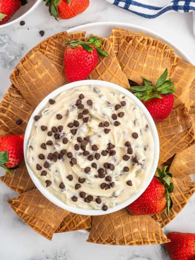 Overhead shot of a bowl with cannoli dip with mini chocolate chips, broken up cone chips, and fresh strawberries.