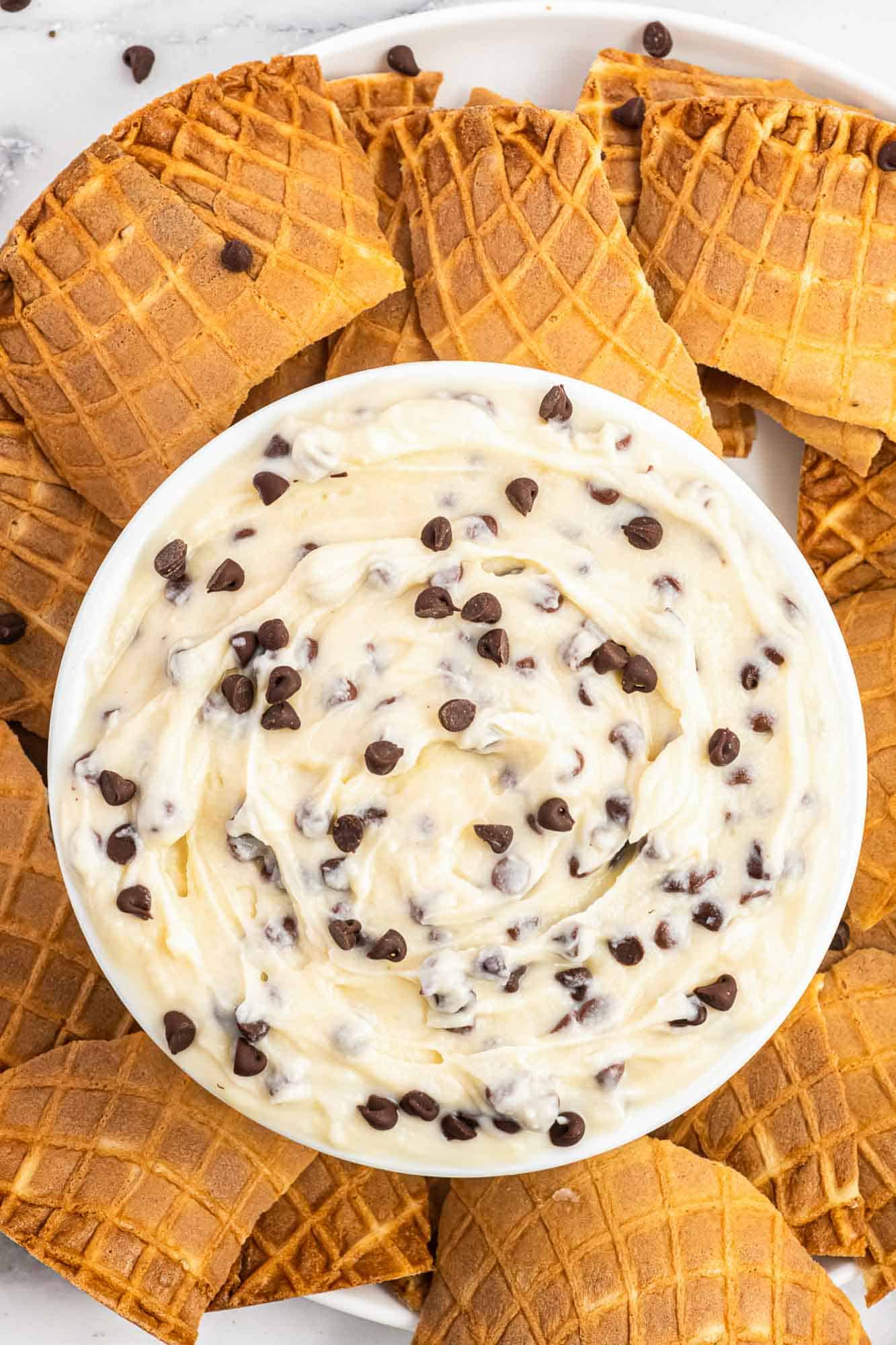 Overhead shot of cannoli dip served in a white bowl with crushed waffle cones