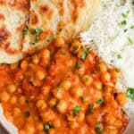 Creamy coconut chickpea curry served in a bowl with white rice, naan, and fresh cilantro.