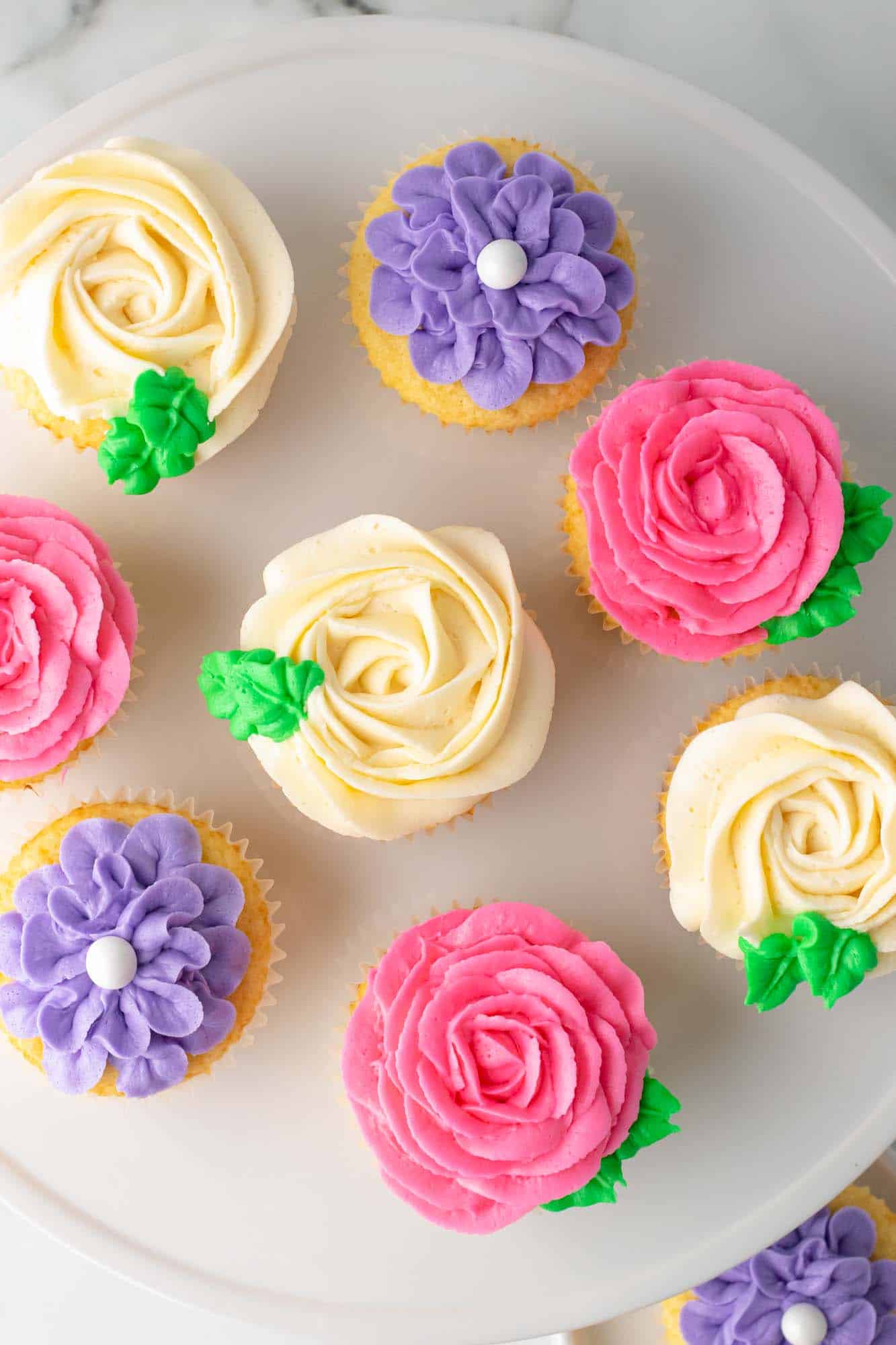 Overhead shot of flower cupcakes placed on a white cake stand