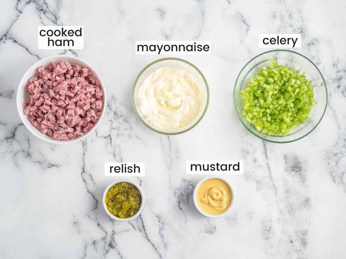 Ingredients needed to make ham salad including chopped ham, mayonnaise, chopped celery, relish, and mustard.