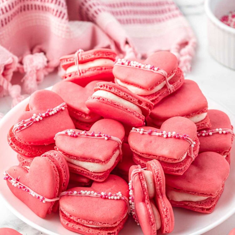 Heart shaped macarons piled on a white plate