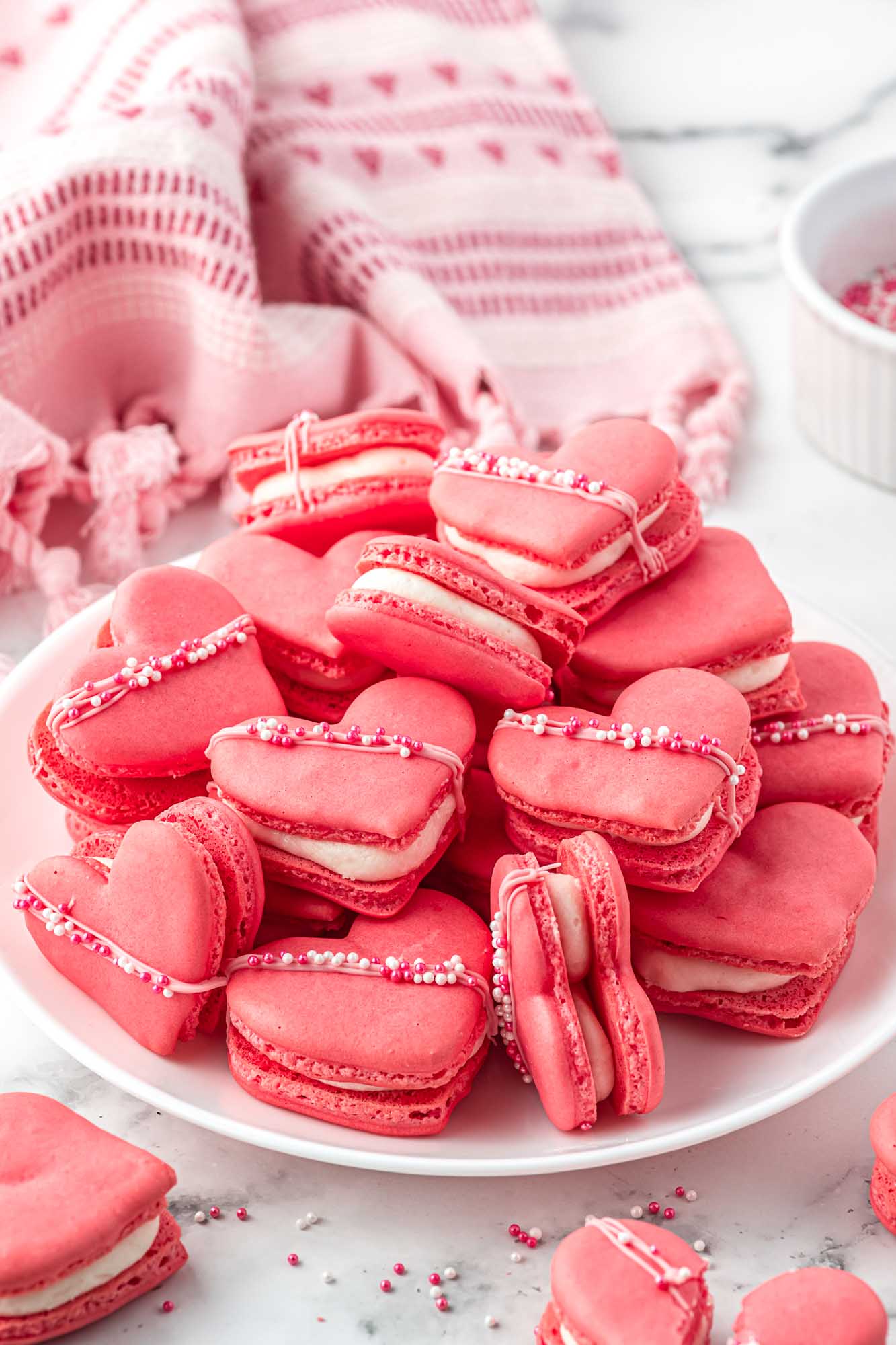 Heart shaped macarons piled on a white plate