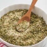 Italian dressing mix in a small white ramekin with a small wooden spoon