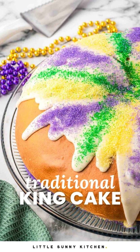 King cake with icing and sanding sugar, with overlay text that says "traditional king cake"