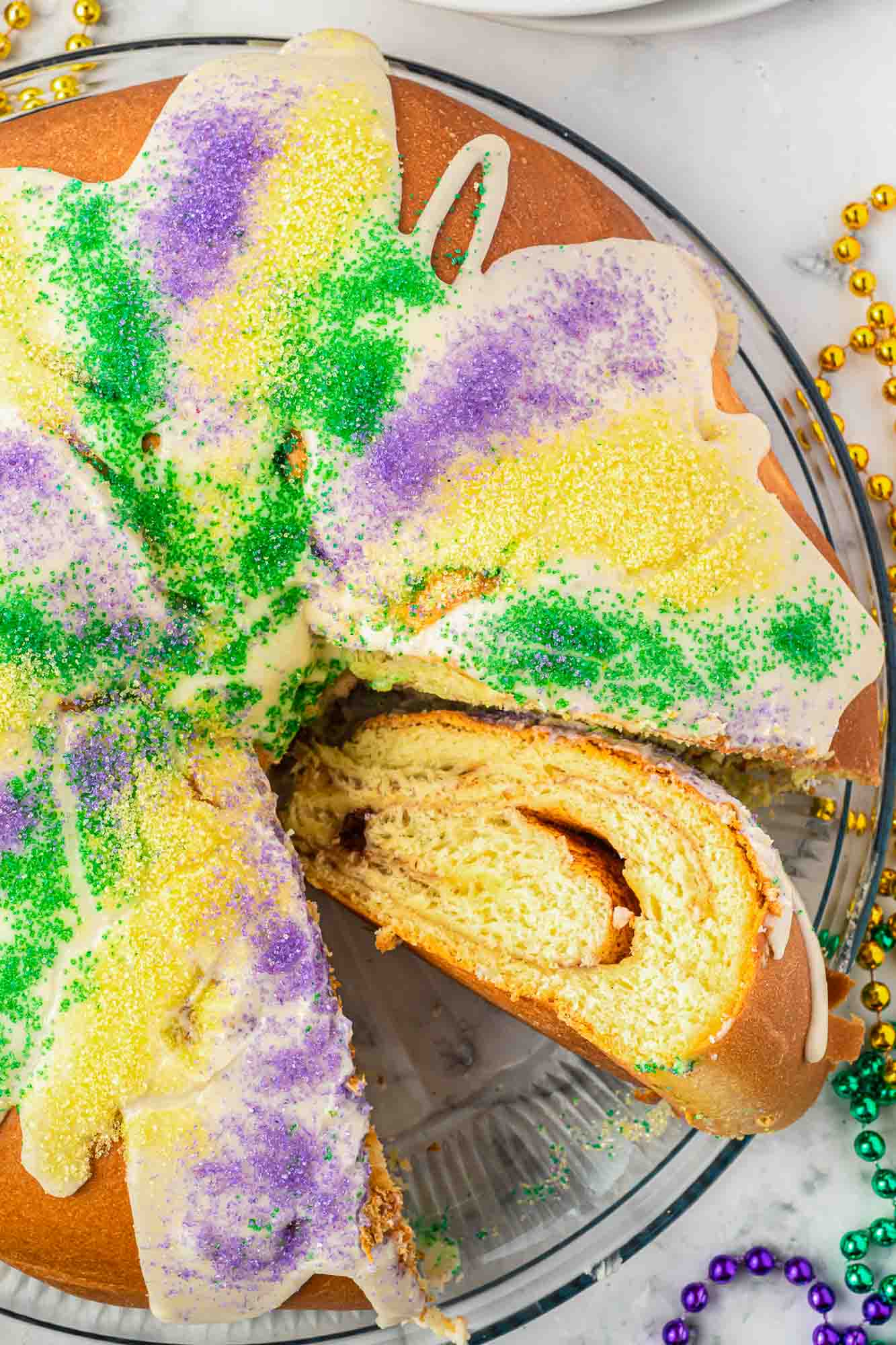 Overhead shot of an iced King cake with a slice