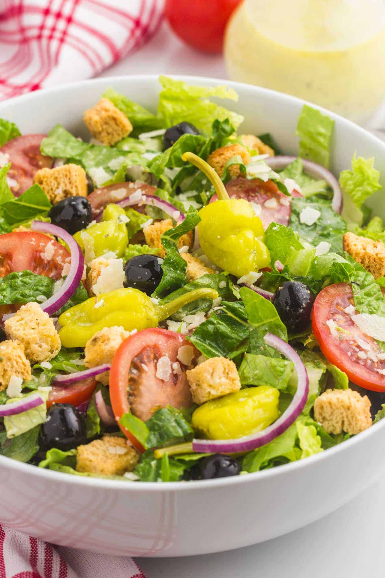 Angle shot of olive garden's salad in a white salad serving bowl