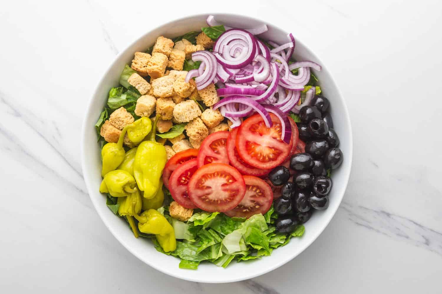 Overhead shot of olive garden's salad ingredients in a bowl before mixing