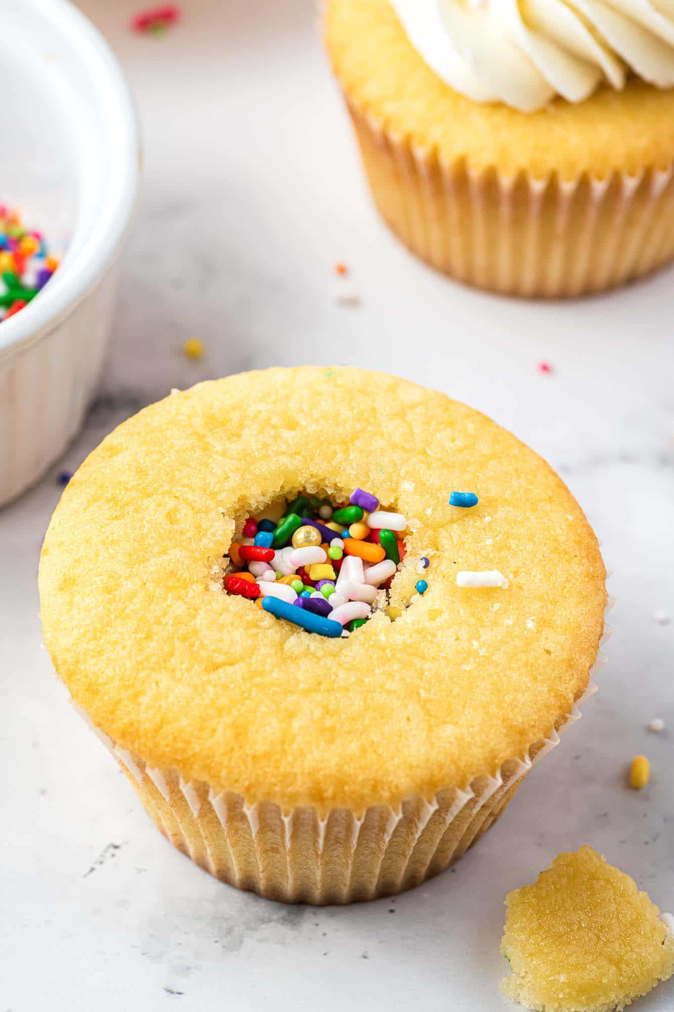 Vanilla cupcake cored and filled with sprinkles