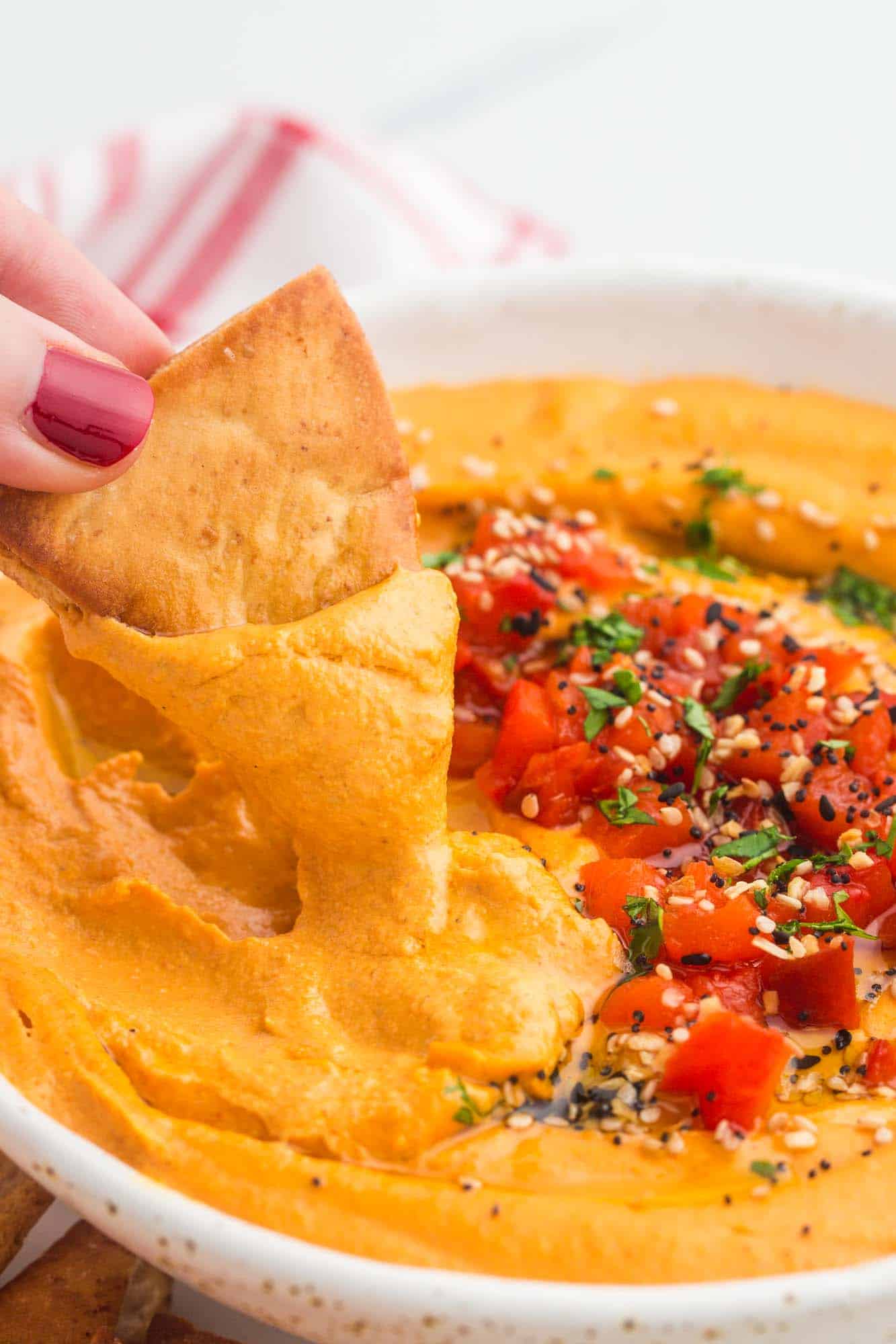 Dipping pita chips in Roasted Red Pepper Hummus