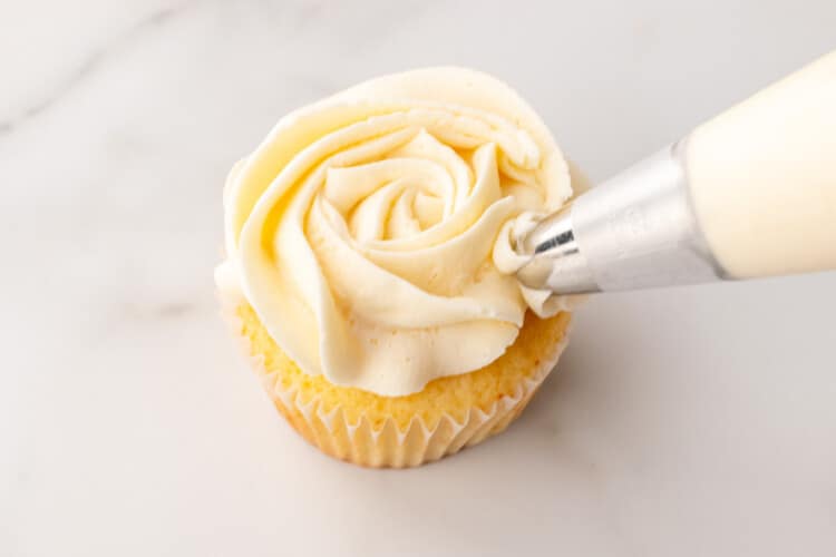 Piping a white rose on a cupcake
