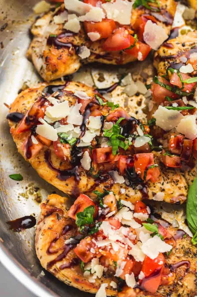 Bsuchetta chicken in a stainless steel skillet with parmesan and balsamic glaze