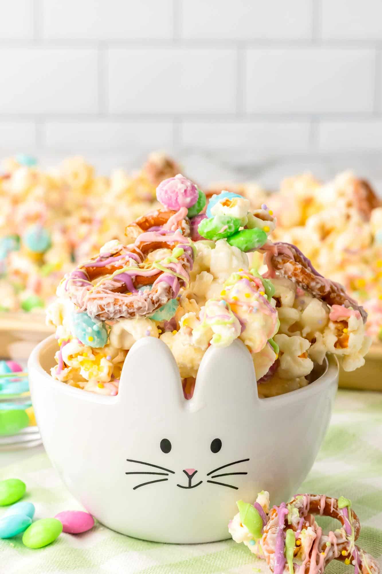 a small white bowl decorated to look like a bunny, filled with white chocolate bunny bait snack mix.